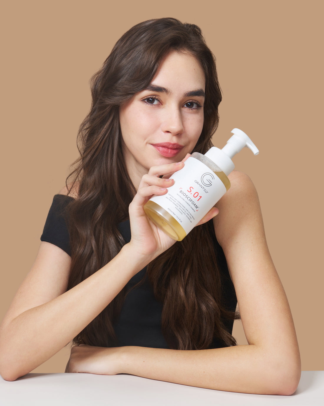 Close-up of model presenting S.01 BIOSCIFOAM, a foaming shampoo targeting hair loss and oily scalp.