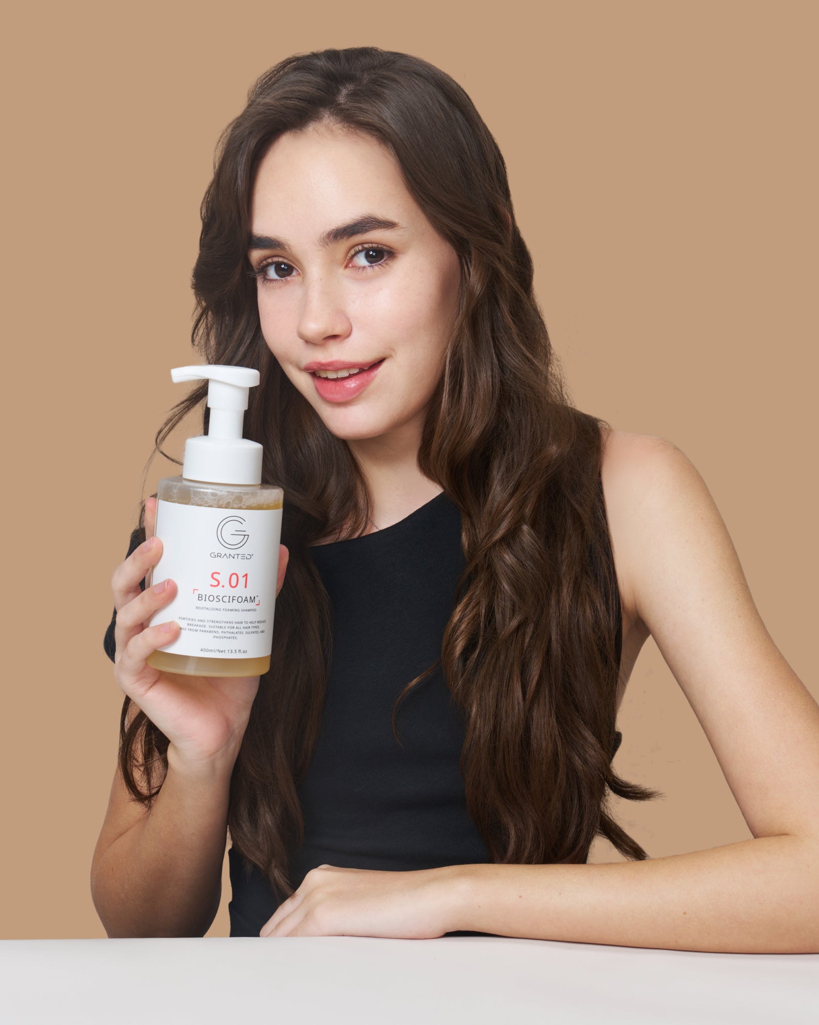 Model holding GRANTED S.01 BIOSCIFOAM foaming shampoo for hair loss and oily scalp, 400ml pump bottle.