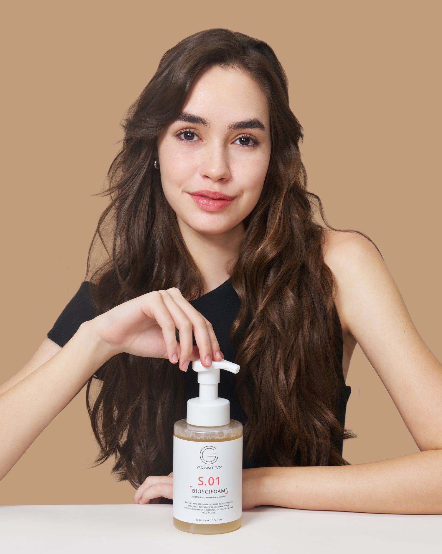 Model touching the pump of GRANTED S.01 BIOSCIFOAM foaming shampoo, care for hair loss and oily scalp.
